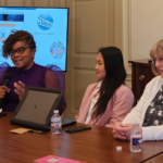 Three women sitting in a table in a women's rights event